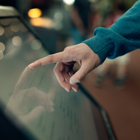 Przybliżenie na dłoń męską z palcem wskazującym, który styka się z ekranem dotykowym.