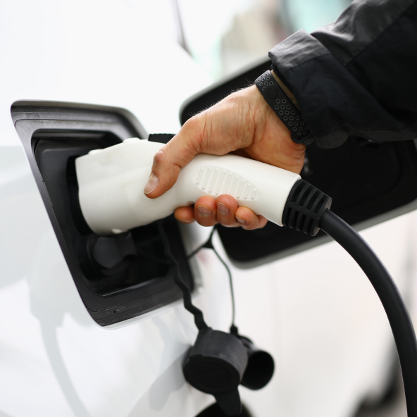 męska ręka trzyma ładowarkę i ładuje samochód