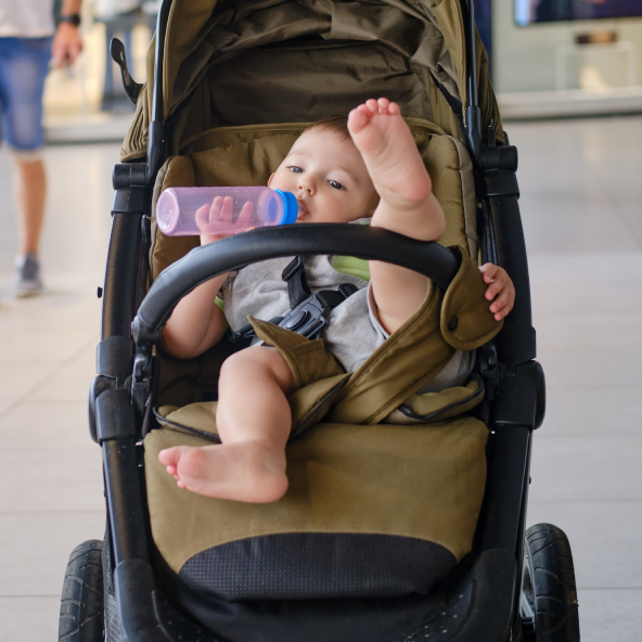 małe dziecko w wózku dziecięcym z butelką w buzi