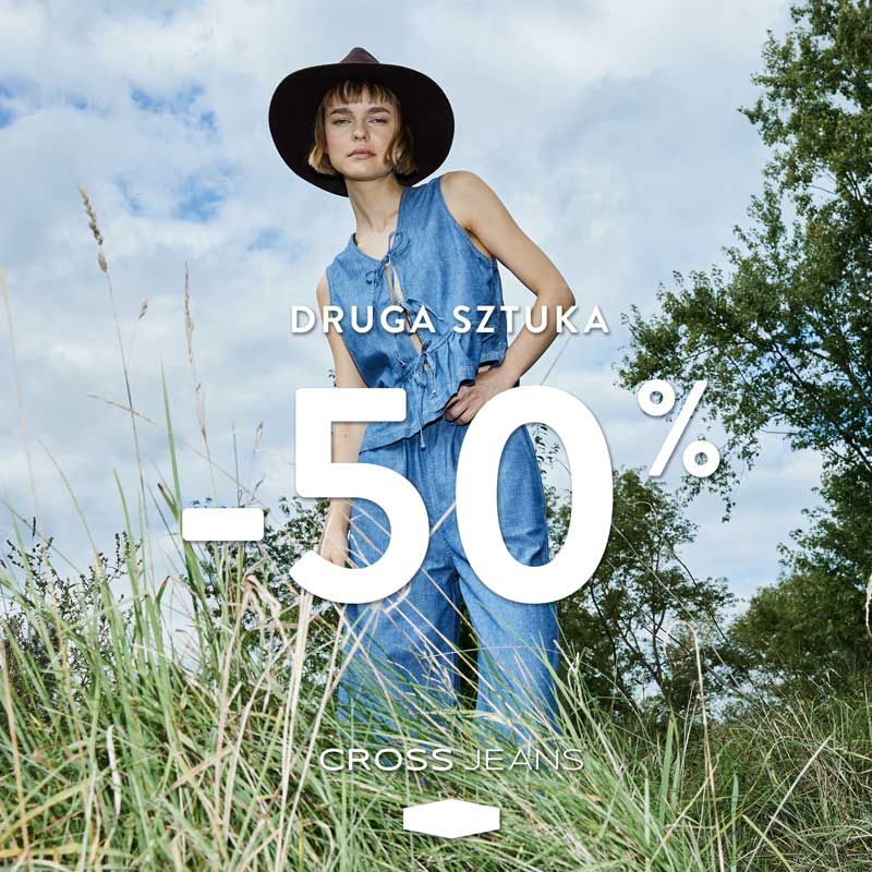 Młoda kobieta w kapeluszu i dżinsowym komplecie (top i spodnie) stoi na tle zielonej trawy i nieba. Na zdjęciu widoczny duży napis DRUGA SZTUKA -50% oraz logo Gross Jeans.
