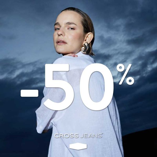 Kobieta w białej koszuli, na tle zachmurzonego nieba, z dużym napisem -50% i logo Cross Jeans.