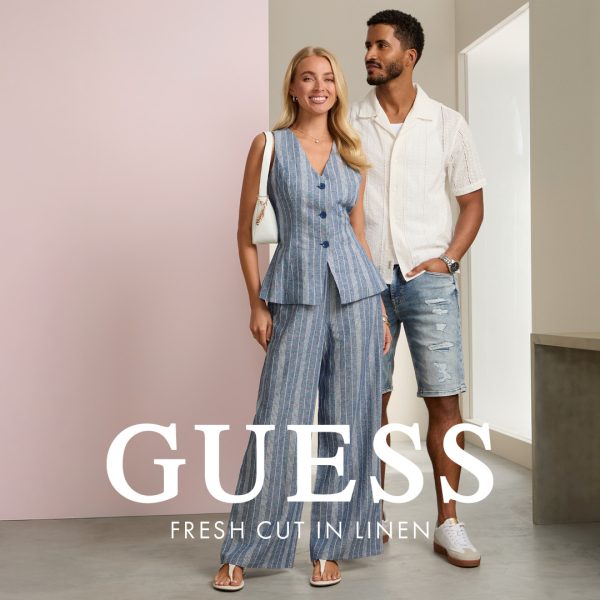 Para w ubraniach z lnianej kolekcji Guess Outlet. Kobieta w niebieskim komplecie w paski, mężczyzna w białej koszuli i szortach.
