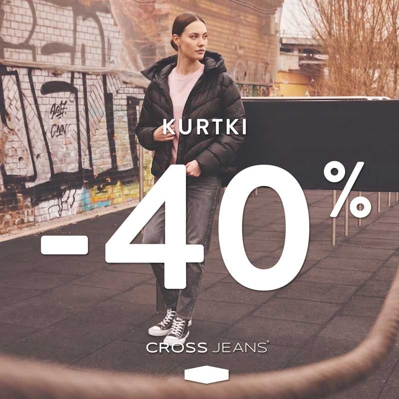 Młoda kobieta w czarnej kurtce puchowej i ciemnych jeansach, stojąca na tle ściany z graffiti. Na zdjęciu widoczny napis KURTKI -40% oraz logo CROSS JEANS.