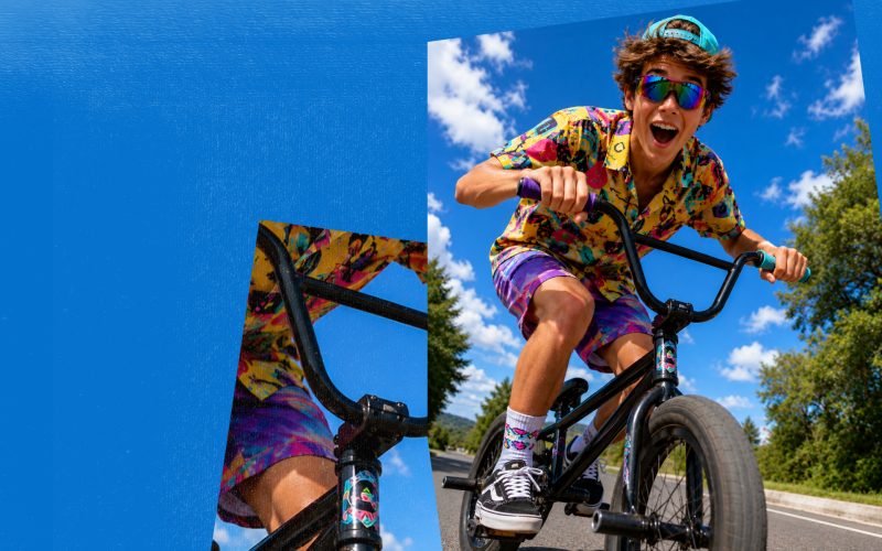 Nastolatek na rowerze BMX w kolorowej koszuli na tle błękitnego nieba – akcja O!dpicuj swój rower w Outlet Parku