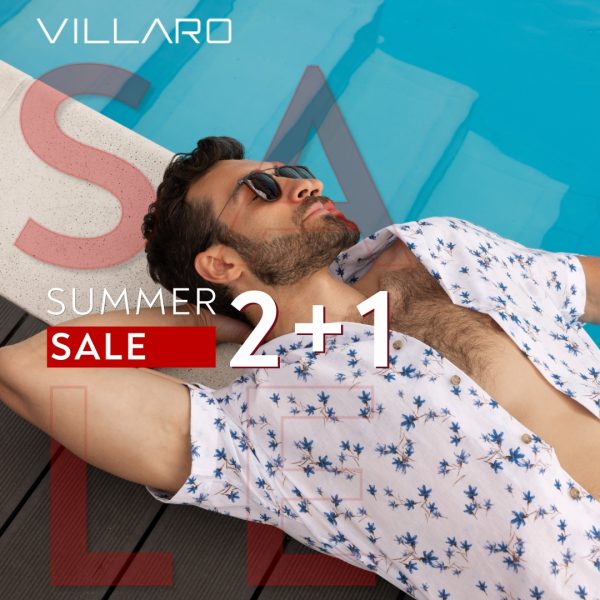 Mężczyzna w okularach przeciwsłonecznych i letniej koszuli w kwiaty, leżący przy basenie, z napisem 'SUMMER SALE 2+1' i logo VILLARO.
