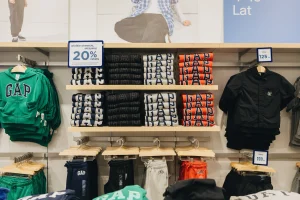 Półki z bluzami i spodniami dresowymi GAP z informacją o 20% rabacie na otwarcie