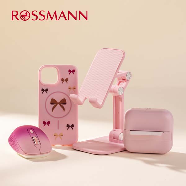 Różowe akcesoria elektroniczne i biurowe marki Forever i Eloy, w tym myszka, etui na telefon, składany uchwyt na telefon i drukarka termiczna, na beżowym tle, z logo Rossmann.