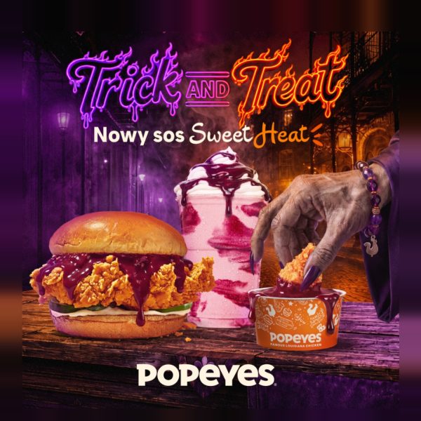 Reklama Popeyes z halloweenową grafiką, przedstawiająca kanapkę z kurczakiem, shake'a i kawałek kurczaka maczany w sosie Sweet Heat przez rękę wiedźmy. Napis "Trick and Treat" i "Nowy sos Sweet Heat".
